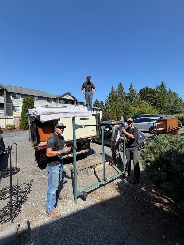 Crew loading furniture and mattresses into the truck for a junk removal job by Classic Cleanouts