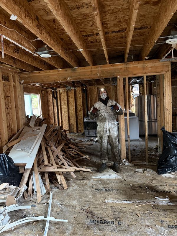 Crew member in protective gear inside a home taken down to the studs during a restoration tear-out by Classic Cleanouts