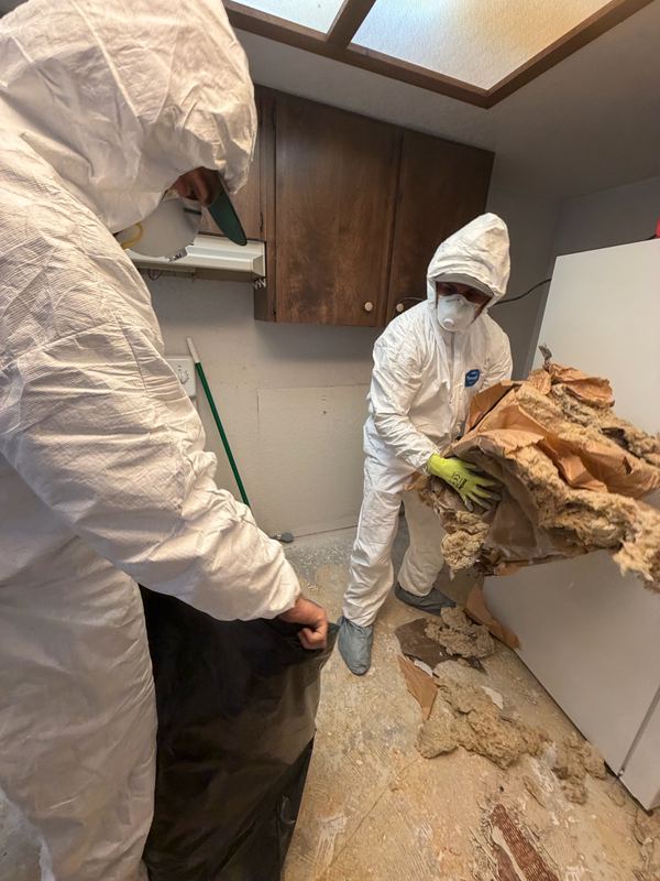 Classic Cleanouts crew in protective gear removing water-damaged materials from a kitchen