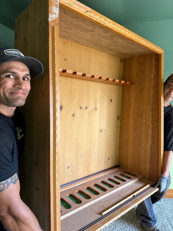 Crew moving a large wooden cabinet out of a home