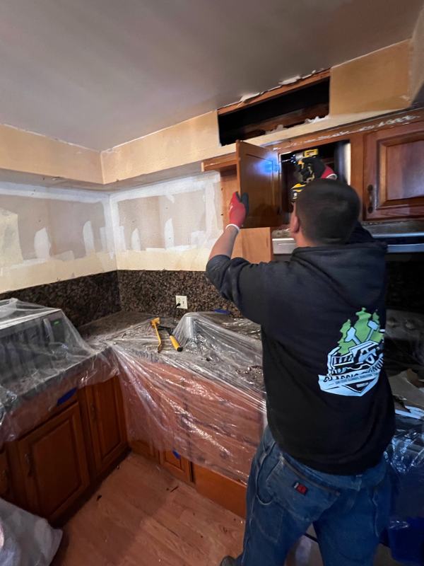 Classic Cleanouts crew member removing kitchen cabinets with counters and appliances covered in plastic during a light demolition job