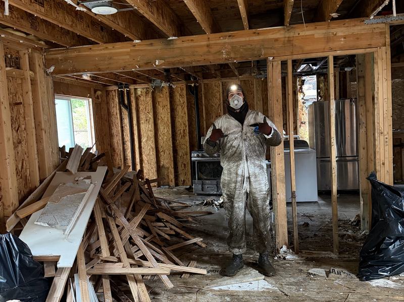 Classic Cleanouts crew member in protective gear inside a home taken down to the studs during a restoration tear-out
